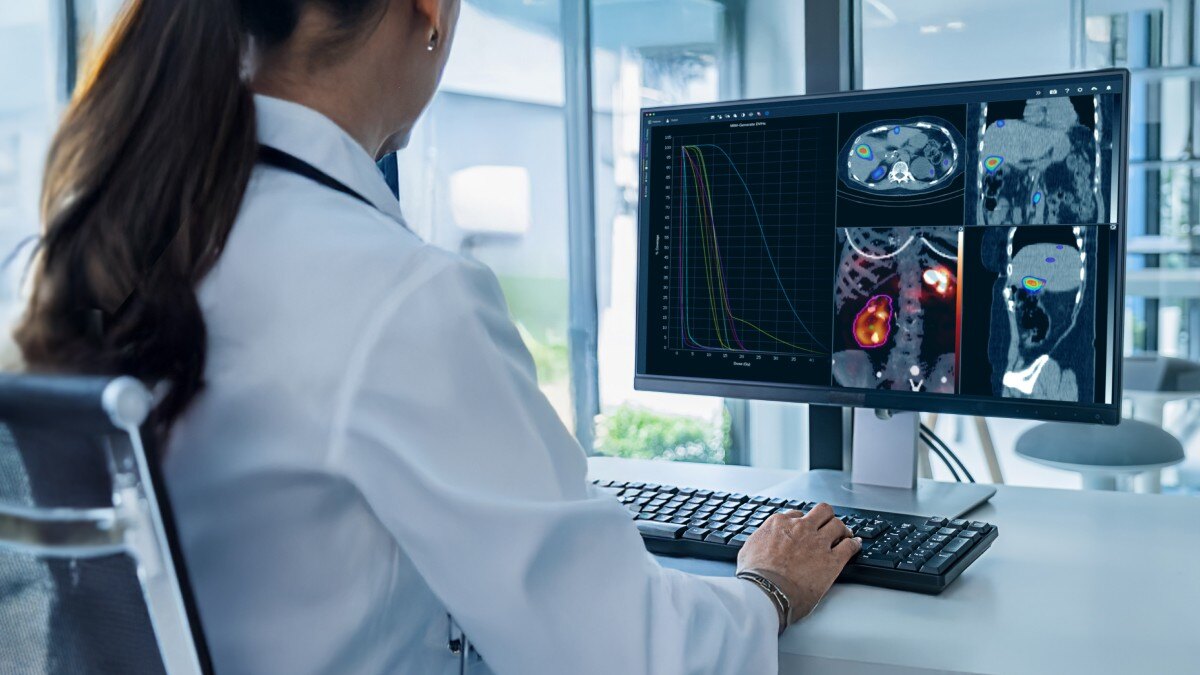 Female doctor sitting behind a computer screen that has medical scans displaying.