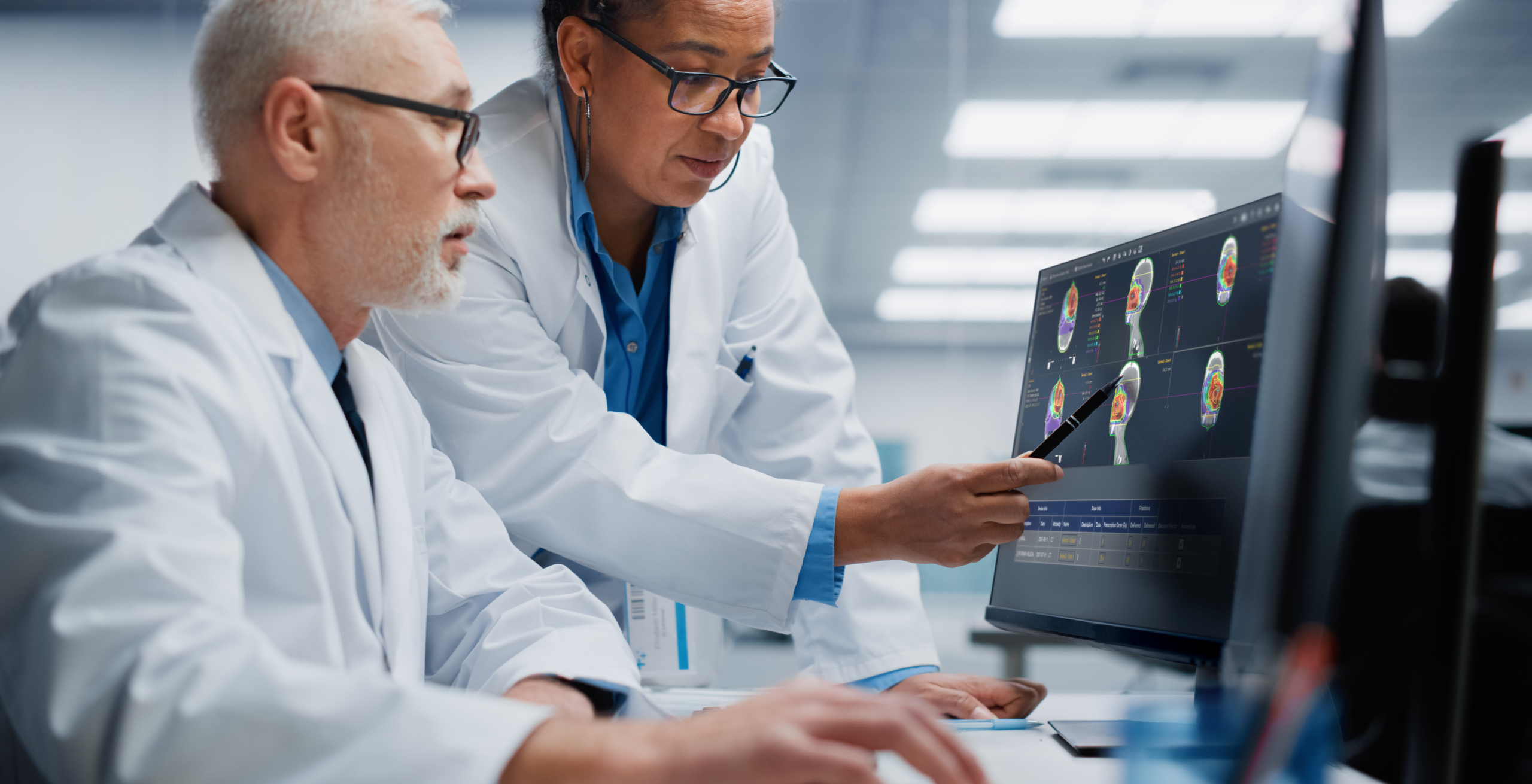 Two doctors looking at medical images on a computer monitor